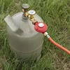 A gas cylinder with a regulator and hose attached, sitting on grass. Produktbild-Vorschau