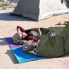 A couple lying in sleeping bags on a beach next to a tent. Náhľad obrázku produktu