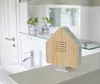 A house-shaped sound machine with a wood-grain front sits on a white surface in a bathroom setting. Produktbild-Vorschau