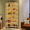 A corner bookshelf filled with various decorative items and books, placed next to a brown armchair and near a window with curtains. Náhled obrázku produktu