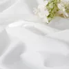 A close-up of white fabric with a small sprig of white flowers. Náhled obrázku produktu