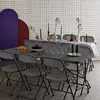A long table set for a party with chairs around it, against a tiled wall with decorative arched panels. Anteprima dell’immagine prodotto