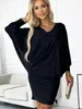 A woman wearing a black dress is posing in a room with a sofa. Anteprima dell’immagine prodotto