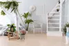 A bright, airy room with a bed, a white wicker chair, plants, and a white spiral staircase. Produktbild-Vorschau