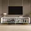 A white TV stand with gold accents is shown in a living room setting, with a TV mounted on the wall above it. Produktbild-Vorschau