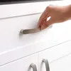 A hand is shown opening a white cabinet drawer with a silver handle. Produktbild-Vorschau