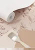 A roll of floral wallpaper is shown with paint swatches and a paintbrush. Náhled obrázku produktu