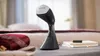 A handheld garment steamer is placed on a table next to folded clothing and a book. Náhľad obrázku produktu