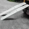 Two silver ramps are positioned on a gray concrete surface, with one end of the ramps leaning on a dark, possibly yellow and black, object. Náhled obrázku produktu