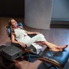 A woman relaxing in a chair next to a projector. Anteprima dell’immagine prodotto