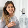 A woman is holding a glass of water next to a large water bottle with a dispenser attached. Náhľad obrázku produktu