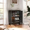 A black shoe cabinet with open doors, filled with various shoes and boots, placed in a room with wooden floors and large windows with sheer curtains. Produktbild-Vorschau