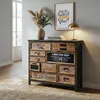 A vintage-style apothecary cabinet with multiple drawers, decorated with various labels and graphics, is placed in a room with a rug and a framed picture on the wall. Podgląd zdjęcia produktu