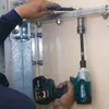 A person is using a Makita impact wrench to tighten a bolt on a metal fixture. Podgląd zdjęcia produktu