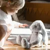 A child is playing with a stuffed bunny on the floor. Produktbild-Vorschau