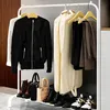 A white metal garment rack with various clothing items and accessories displayed on it, including jackets, pants, boots, and handbags. Náhled obrázku produktu