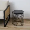 Two nesting hexagonal side tables with black metal wire bases and black tops, placed on a wooden floor next to a chair with a cane back. Produktbild-Vorschau