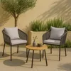 Two chairs and a small table set up on a patio with plants and a tree. Anteprima dell’immagine prodotto