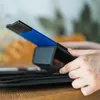 A person's hands are holding a black case with blue and black pencils sticking out of it. Podgląd zdjęcia produktu