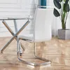 A white dining chair with a chrome frame is shown next to a glass-topped dining table with a chrome base. A plant in a concrete pot is visible in the background. Produktbild-Vorschau