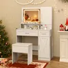A white vanity table with a lighted mirror, drawers, and a cabinet, set up in a room decorated for Christmas with a tree and festive lights. Voir les images du produit