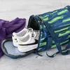 A duffel bag with shoes and a purple hoodie next to it. Produktbild-Vorschau