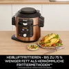 A Ninja multicooker is shown on a wooden countertop next to a plate of cooked chicken and a small bowl of dip. Produktbild-Vorschau