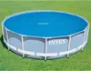 An Intex round solar pool cover is shown on top of an above-ground pool, which is set up on a grassy lawn. Voir les images du produit