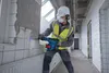 A construction worker is using a power tool to break down a tiled wall in a building under renovation. Produktbild-Vorschau