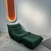 A green sofa and ottoman are placed on a rug in front of a white wall with an illuminated oval feature. Voir les images du produit