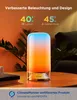 A Govee LED table lamp with a gradient light effect is placed on a wooden table next to a book and a plant. The background is a warm, blurred interior scene. Produktbild-Vorschau