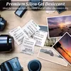 Silica gel packets are arranged on a wooden surface around camera equipment and photographs. Produktbild-Vorschau