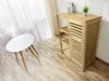 A bathroom cabinet with shelves and a slatted door, next to a small white table, in a room with sheer curtains and wooden flooring. Produktbild-Vorschau