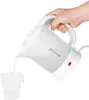 A hand is pouring water from a white electric kettle into a clear measuring cup. Voir les images du produit