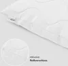 A close-up view of a white pillow, showing a zipper detail and a brand tag. Produktbild-Vorschau