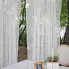 A table setting with decorative elements in an outdoor, natural setting, partially obscured by white lace curtains. Produktbild-Vorschau