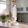 A Wessper water carbonator is shown on a kitchen counter next to a glass of water with lemon. Produktbild-Vorschau