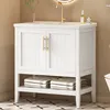 A white bathroom vanity with gold hardware sits on a patterned floor, with towels folded on the open shelf below. Náhľad obrázku produktu