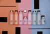 A collection of reusable water bottles of various sizes and colors arranged in a line on a split-color background. Produktbild-Vorschau