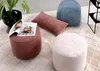 A collection of round and rectangular poufs/ottomans in various colors on a textured rug, with a plant and a magazine. Náhľad obrázku produktu