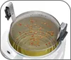 A close-up view of a deep fryer basket filled with food being fried in hot oil. Produktbild-Vorschau