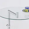A close-up of a round glass side table with a chrome metal frame. A small decorative cup and saucer are on the table. Produktbild-Vorschau