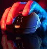 A hand is holding a black gaming mouse, illuminated by red and blue lights. Produktbild-Vorschau