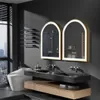 A modern bathroom with a toilet, double vanity with sinks and mirrors, and a window with a city view. Náhled obrázku produktu