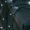 A string of white LED lights draped over a stone surface. Produktbild-Vorschau