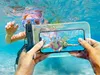 A child wearing a snorkel mask is underwater, holding a waterproof phone case with a phone inside showing a picture of the child and another person also underwater. Náhľad obrázku produktu