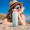 A person lying on a beach with a water bottle in the foreground. Anteprima dell’immagine prodotto