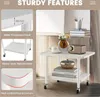 A collage of images showcasing the features of a white, two-tiered rolling table with a metal frame. One section shows a close-up of the 18mm thickened panel, another displays the metal frame and wheels, and a third highlights the rounded corners. The main Produktbild-Vorschau