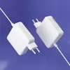 Two white power adapters are shown against a light purple background. Podgląd zdjęcia produktu