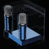 Two blue microphones are displayed inside a transparent cube-like structure, resting on a blue platform. The background is black. Náhled obrázku produktu